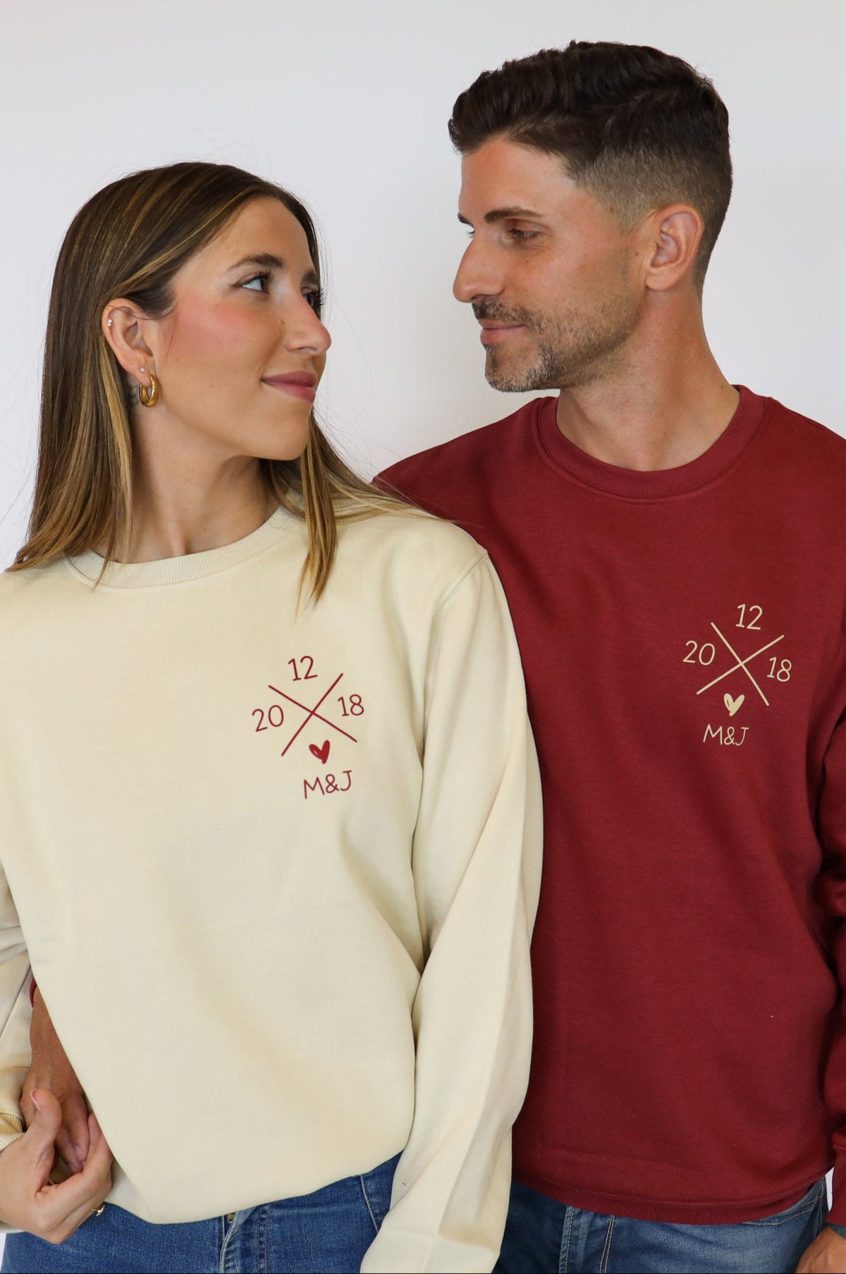 Pareja con sudaderas Cruz Fecha beige y granate personalizadas