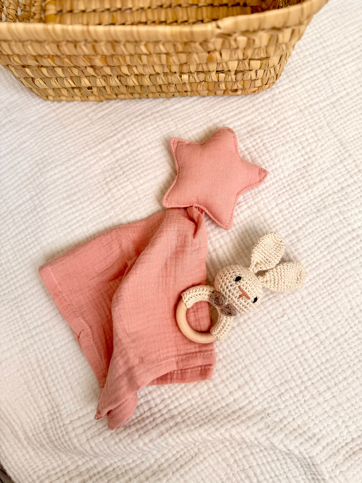 Doudou con estrella rosa junto a sonajero de conejo