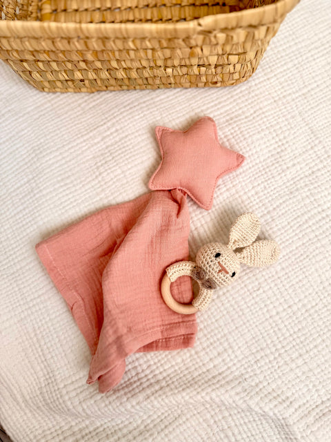Doudou con estrella rosa junto a sonajero de conejo